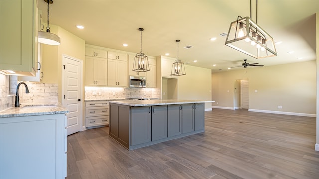 kitchen featuring light stone counters, pendant lighting, white cabinets, a kitchen island, and hardwood / wood-style floors