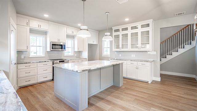 kitchen featuring white cabinets, a center island, light hardwood / wood-style floors, and tasteful backsplash