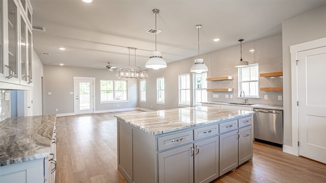 kitchen featuring dishwasher, a center island, light hardwood / wood-style flooring, pendant lighting, and decorative backsplash