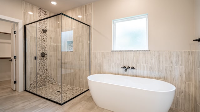 bathroom with tile walls and separate shower and tub