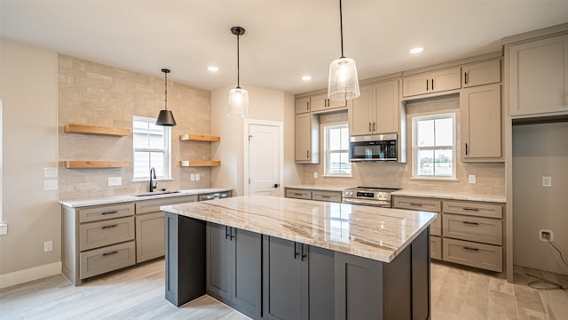 kitchen with a kitchen island, light stone countertops, appliances with stainless steel finishes, tasteful backsplash, and sink