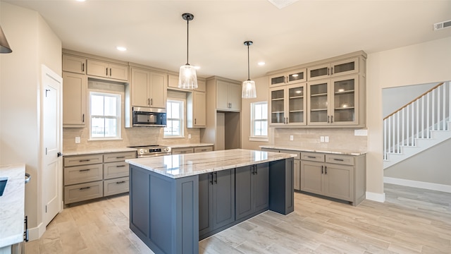 kitchen featuring light stone counters, stainless steel appliances, and gray cabinetry