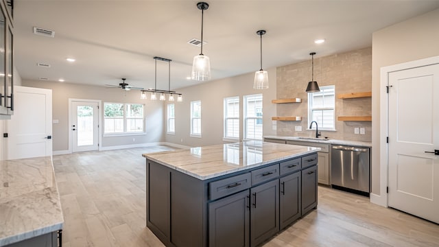 kitchen with light hardwood / wood-style flooring, ceiling fan, a kitchen island, decorative backsplash, and stainless steel dishwasher