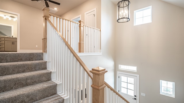 stairs featuring plenty of natural light, ceiling fan, and a high ceiling