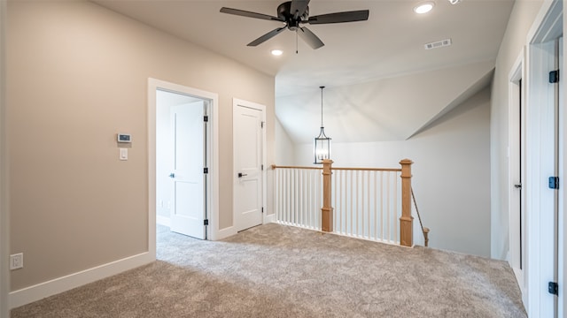 carpeted spare room featuring vaulted ceiling and ceiling fan