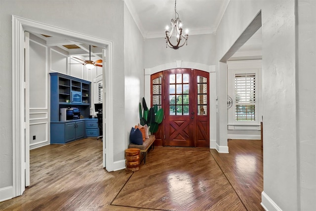 foyer entrance with ceiling fan with notable chandelier, dark hardwood / wood-style floors, and ornamental molding