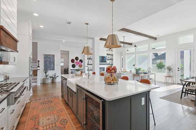 kitchen with visible vents, light wood-style flooring, a sink, wine cooler, and stainless steel gas cooktop