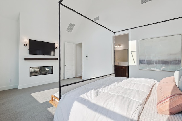 bedroom featuring light colored carpet, high vaulted ceiling, and ensuite bath