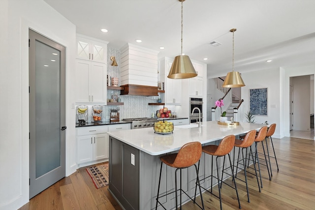 kitchen featuring light hardwood / wood-style floors, decorative backsplash, a spacious island, and custom exhaust hood