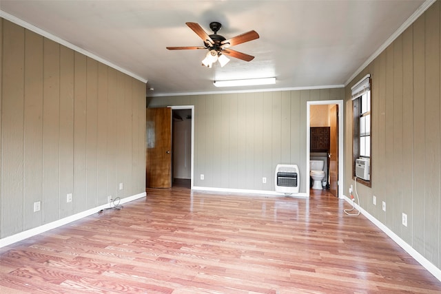 unfurnished room featuring heating unit, wood walls, and light hardwood / wood-style flooring