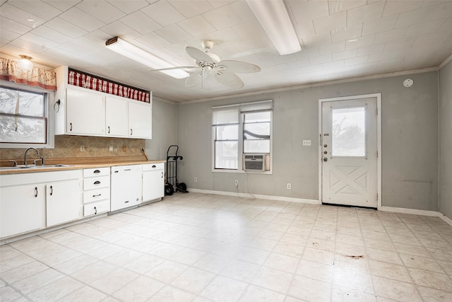 kitchen featuring decorative backsplash, white cabinetry, sink, and ceiling fan