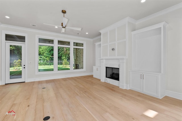 unfurnished living room featuring a premium fireplace, crown molding, light hardwood / wood-style flooring, and ceiling fan