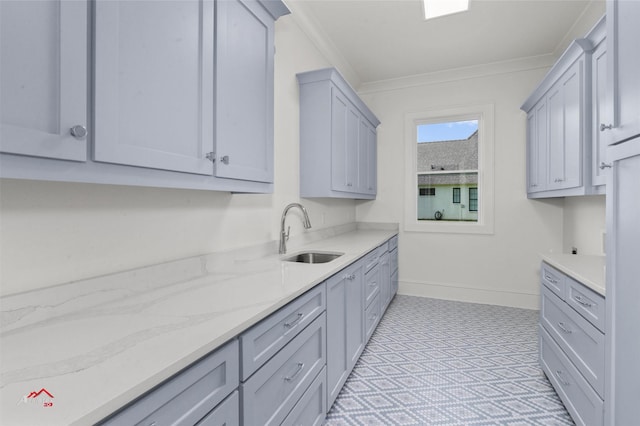 kitchen with light stone counters, sink, gray cabinets, and crown molding