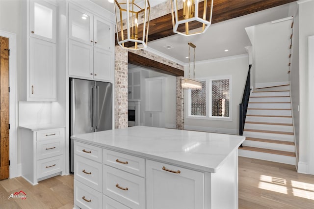 kitchen with light wood-type flooring, pendant lighting, white cabinets, and a center island