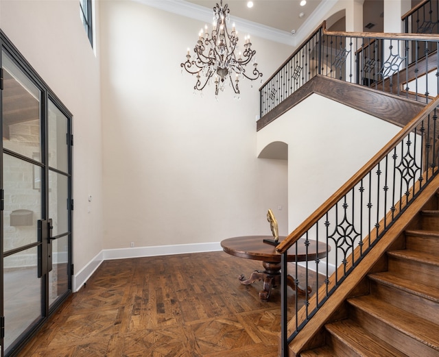 stairs with parquet floors, ornamental molding, a towering ceiling, and a chandelier