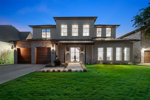 contemporary house featuring a yard, concrete driveway, a standing seam roof, metal roof, and a garage