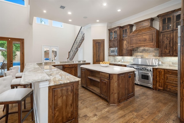 kitchen featuring custom range hood, glass insert cabinets, a center island, stainless steel appliances, and french doors