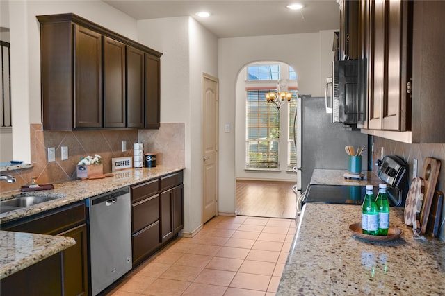 kitchen featuring light stone counters, appliances with stainless steel finishes, dark brown cabinetry, sink, and light hardwood / wood-style floors