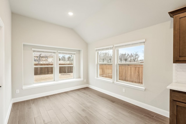 unfurnished dining area featuring lofted ceiling and light hardwood / wood-style floors