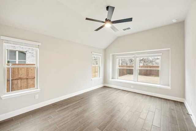 empty room with lofted ceiling, wood-type flooring, and a healthy amount of sunlight