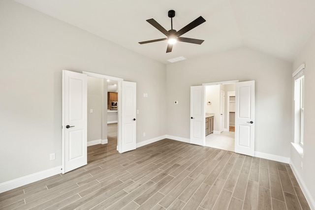 unfurnished bedroom with lofted ceiling, ensuite bath, light hardwood / wood-style flooring, and ceiling fan