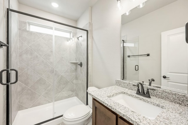 bathroom featuring vanity, an enclosed shower, and toilet