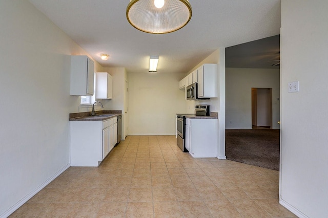 kitchen featuring stainless steel appliances, a sink, white cabinetry, baseboards, and dark countertops