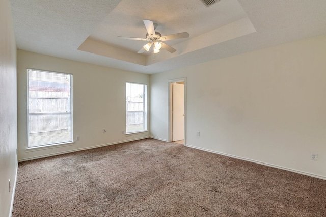 carpeted spare room with baseboards, a ceiling fan, a raised ceiling, and a textured ceiling