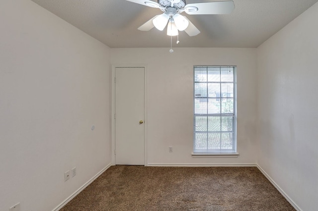 carpeted spare room featuring ceiling fan and baseboards