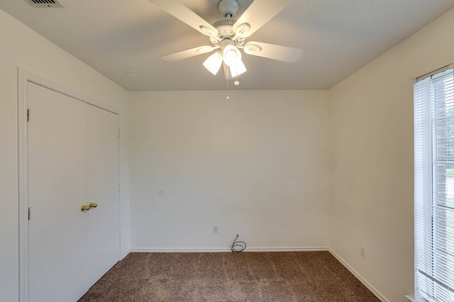 carpeted spare room with ceiling fan, a textured ceiling, visible vents, and baseboards