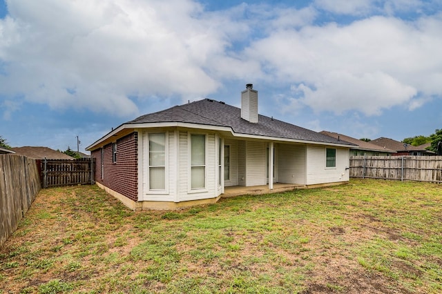 back of house featuring a fenced backyard, a chimney, a lawn, and a patio