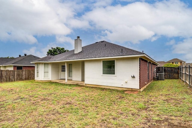 rear view of house featuring cooling unit, a fenced backyard, a lawn, and a chimney