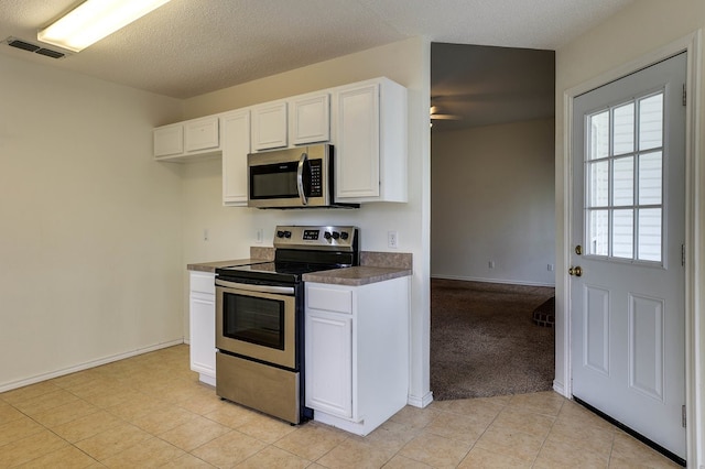 kitchen featuring a textured ceiling, stainless steel appliances, visible vents, white cabinetry, and dark countertops