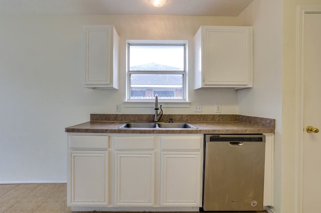 kitchen with dishwasher, dark countertops, a sink, and white cabinetry