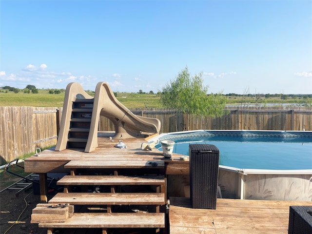 view of swimming pool featuring a water slide and a wooden deck