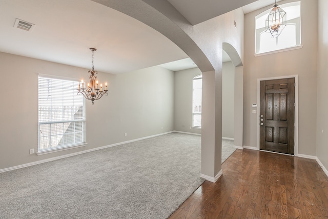 carpeted foyer entrance featuring a notable chandelier