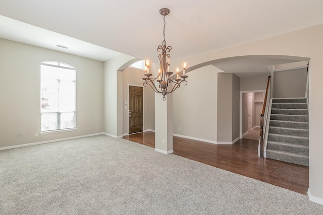 unfurnished room featuring dark colored carpet and a notable chandelier