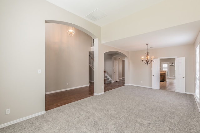 carpeted spare room featuring a chandelier