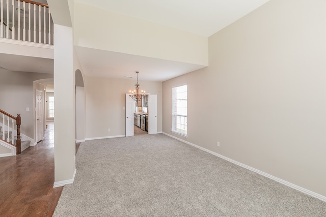 unfurnished living room featuring carpet flooring, a towering ceiling, and a chandelier