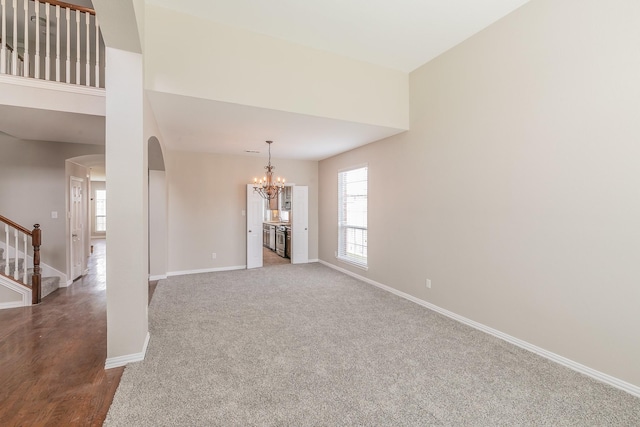 spare room featuring carpet flooring and a chandelier