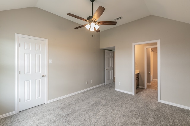 unfurnished bedroom featuring ensuite bath, carpet, ceiling fan, and vaulted ceiling