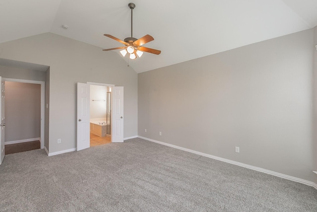 unfurnished bedroom featuring vaulted ceiling, light colored carpet, ensuite bathroom, and ceiling fan