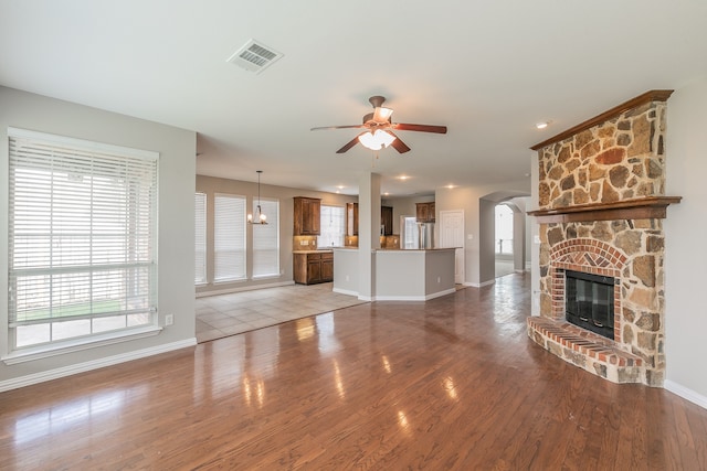 unfurnished living room featuring tile patterned floors, a stone fireplace, and ceiling fan