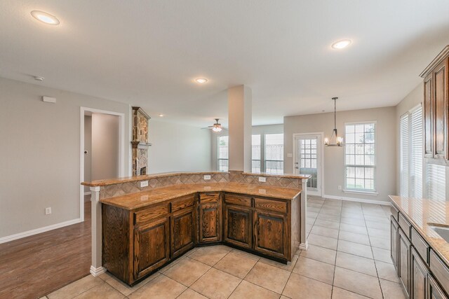 kitchen with light tile patterned flooring, ceiling fan with notable chandelier, and decorative light fixtures