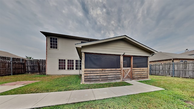 back of house with a lawn and a sunroom