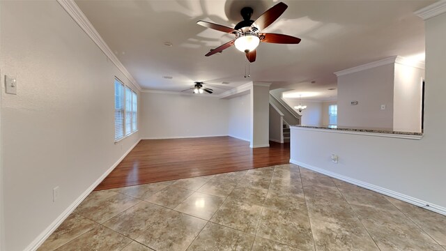 tiled spare room with ceiling fan with notable chandelier and crown molding