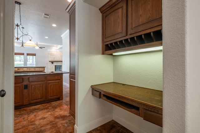 kitchen featuring ceiling fan, ornamental molding, and a fireplace