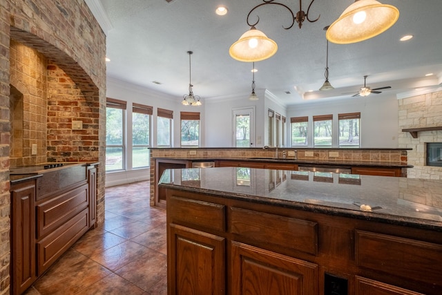 kitchen with sink, pendant lighting, dark stone counters, and ornamental molding