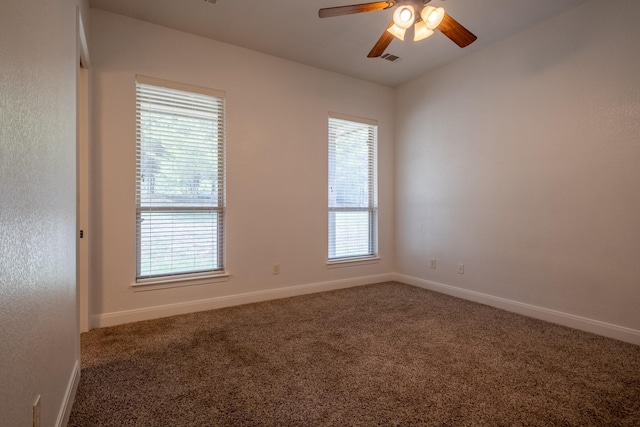 carpeted spare room featuring ceiling fan and a healthy amount of sunlight