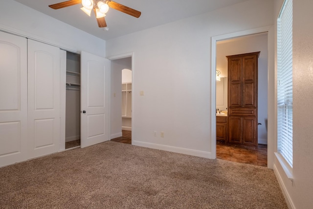 unfurnished bedroom with a closet, ceiling fan, carpet, and ensuite bath